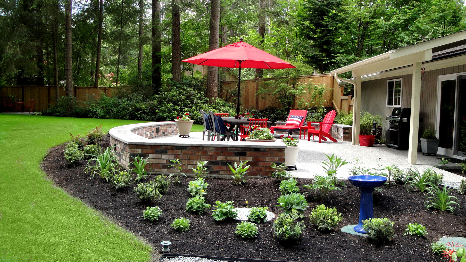 Grina Landscape Design Gig Harbor featuring a red umbrella on the patio and surrounding landscaping