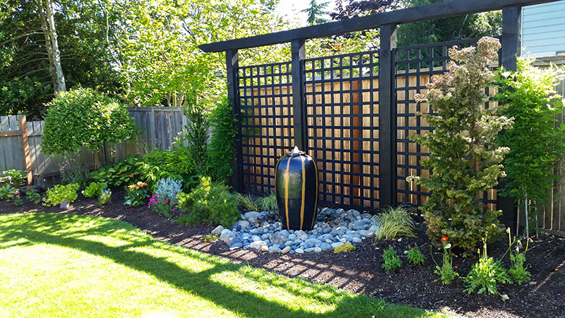 A new lattice arbor backdrop and bubbling water feature now is the yard’s primary focus.